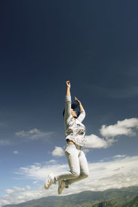 Low angle view of woman jumping against clear sky