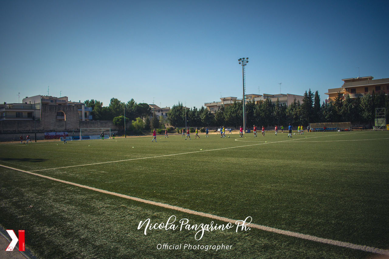 GROUP OF PEOPLE ON SOCCER FIELD AGAINST SKY