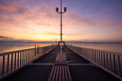 Pier over sea against sky during sunset