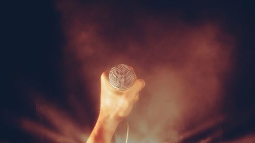 Close-up of human hand holding microphone at night