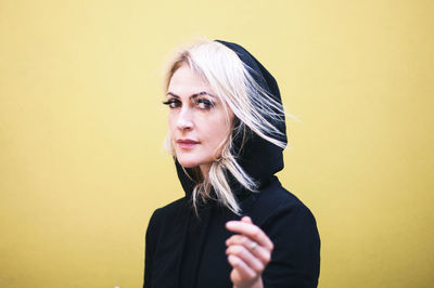 Portrait of a beautiful young woman against yellow background