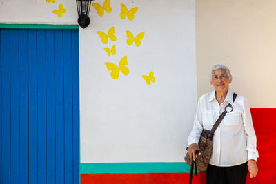 Portrait of young woman standing against wall