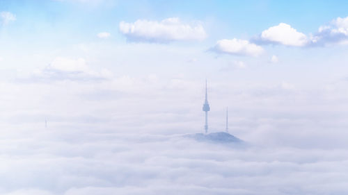 Low angle view of communications tower against cloudy sky