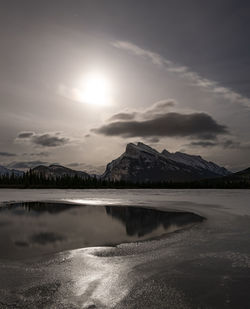 Scenic view of lake by mountains against sky during sunset