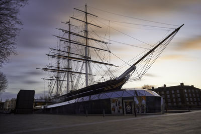 Sailboats in city against sky at sunset