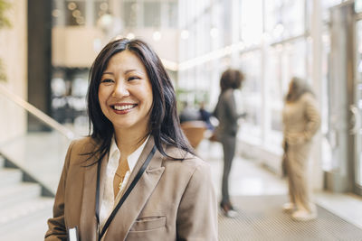 Smiling mature businesswoman standing at networking event in convention center