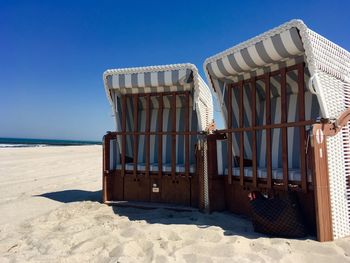 Hooded beach chairs against clear blue sky