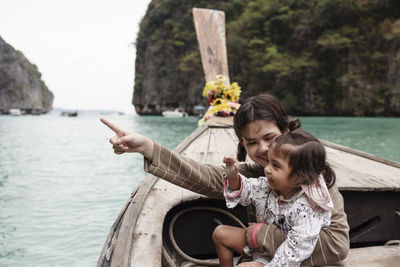 Mother and daughter sitting in traditional boat in canyon