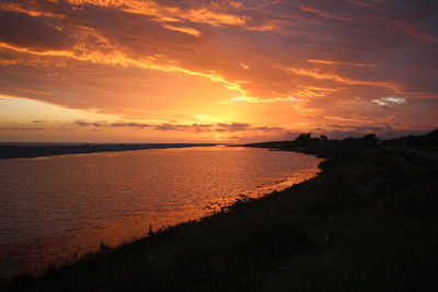 Scenic view of sea against dramatic sky during sunset