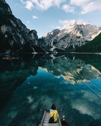 Rear view of woman sitting on steps by lake