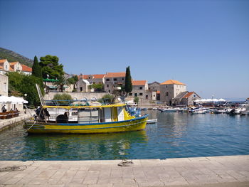 Buildings by river against clear blue sky