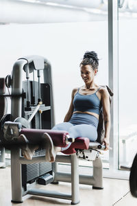 Smiling sportswoman exercising on weightlifting machine in gym