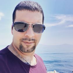 Portrait of man with sunglasses against sea and sky