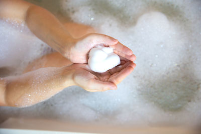 Directly above view of hand holding soap sud in bathtub