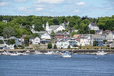 Houses by sea against sky in city