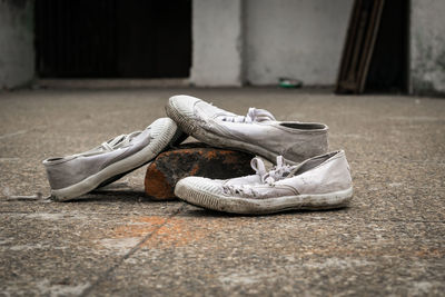 Close-up of weathered canvas shoes on footpath