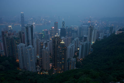 High angle view of illuminated cityscape in foggy weather at dusk