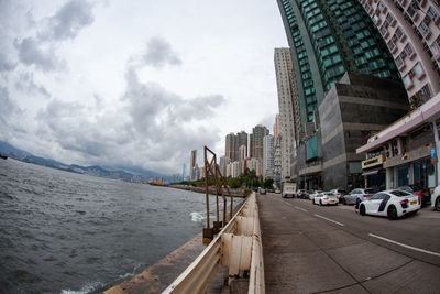 City street by modern buildings against sky