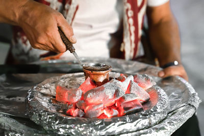 Cooking of turkish coffee by classical method in turk on coals, men's hands close-up