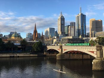 Princes bridge over yarra river by buildings against sky