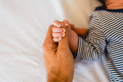 Cropped hand of mother holding baby girl hand