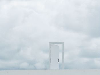 Digital composite image of door frame against cloudy sky