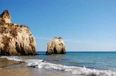 Rock formation at beach against sky