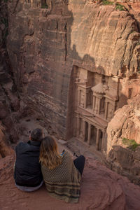 Rear view of people sitting on rock