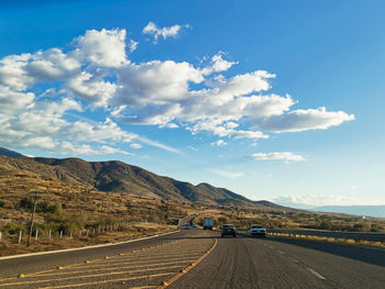 Road by mountains against sky
