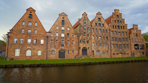 Buildings by river against sky