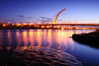 View of suspension bridge over river at night