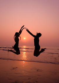 Silhouette people on beach against sky during sunset