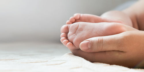 Mother holding baby feet in hands. legs of newborn in parents hand. children's  little toes 