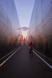 People walking on bridge in city against clear sky