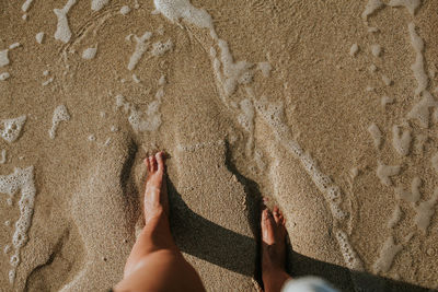 Low section of woman legs on sand at beach