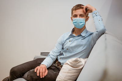Man protective mask sits on the couch person