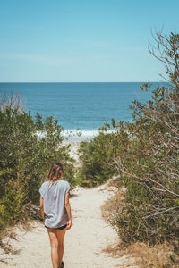 Blond girl on the path to a secret beach 