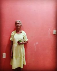 Woman standing against red wall