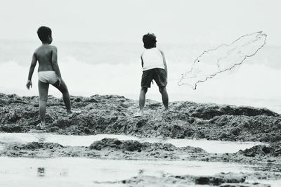 Children standing on beach against sky