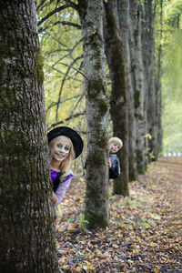 Portrait of young woman standing in forest in halloween costume 