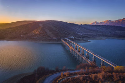 Bridge over river against sky during sunset