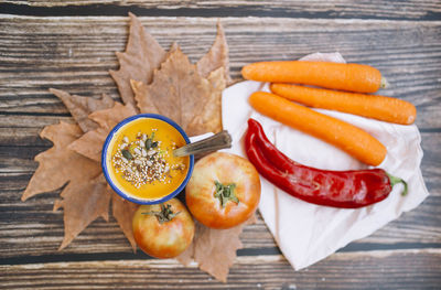 Vegan pumpkin cream in an enameled mug with vegetables, peppers leek and tomatoes