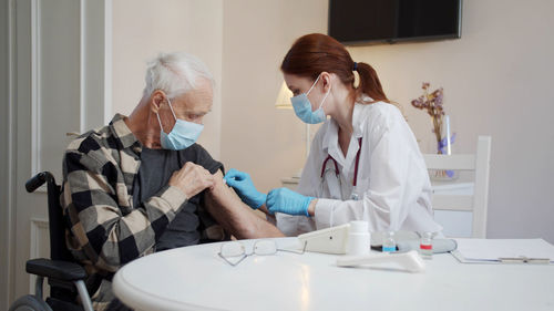 Doctor wearing mask vaccinating senior patient