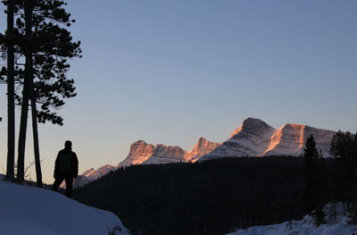 Rear view of man standing on mountain against clear sky