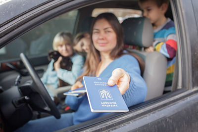 Portrait of young woman using mobile phone while sitting in car