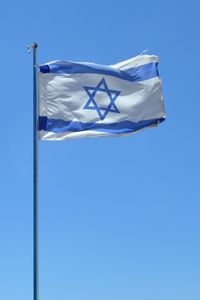 Low angle view of flag against blue sky