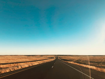 Road passing through landscape against blue sky