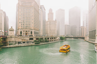 Ferry boat sailing on river against buildings