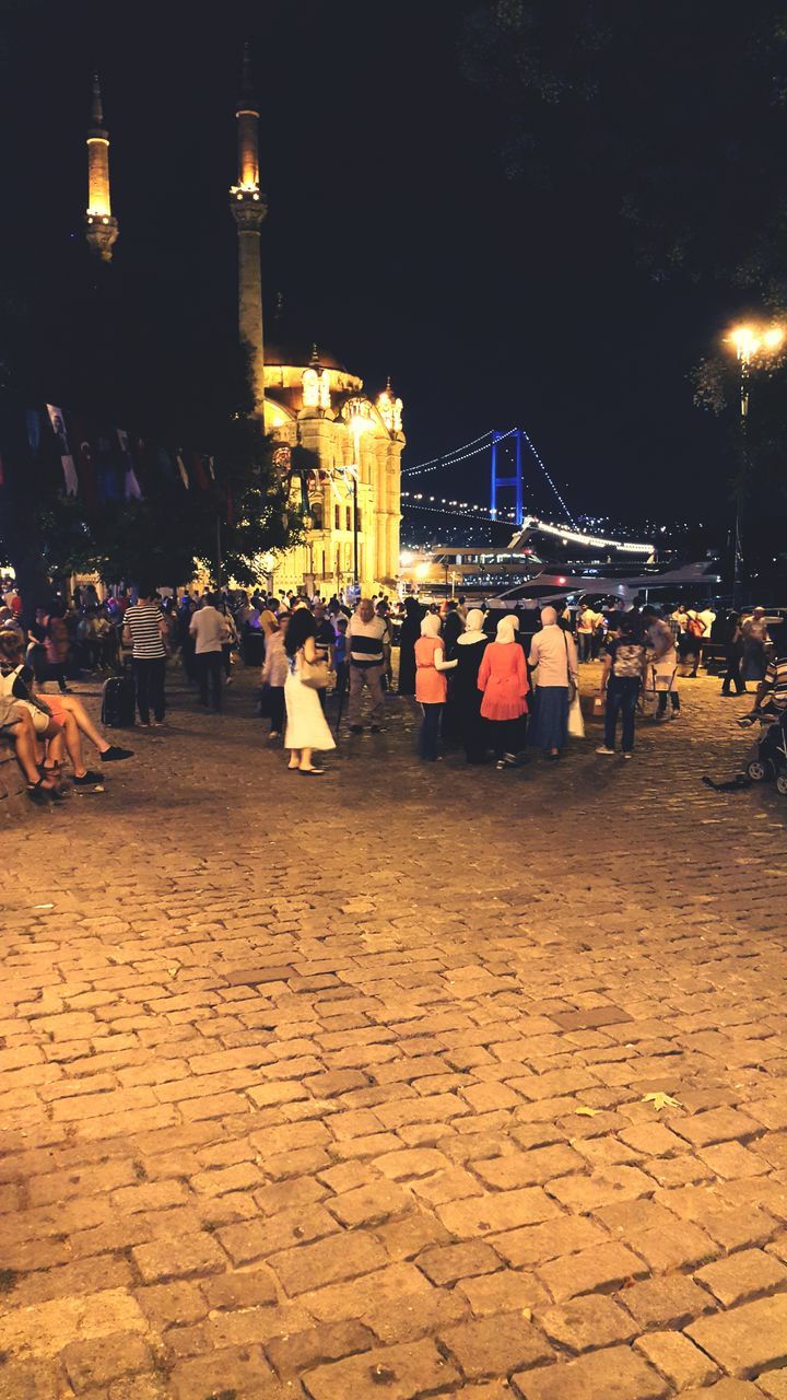 illuminated, night, building exterior, architecture, built structure, city, street, lighting equipment, street light, cobblestone, the way forward, incidental people, city life, outdoors, travel destinations, footpath, road, paving stone, transportation, travel