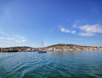 Scenic view of sea by buildings against blue sky